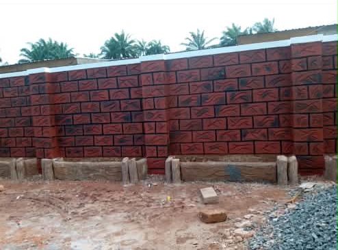 Red brick-pattern fence wall with white coping and wood-effect planters