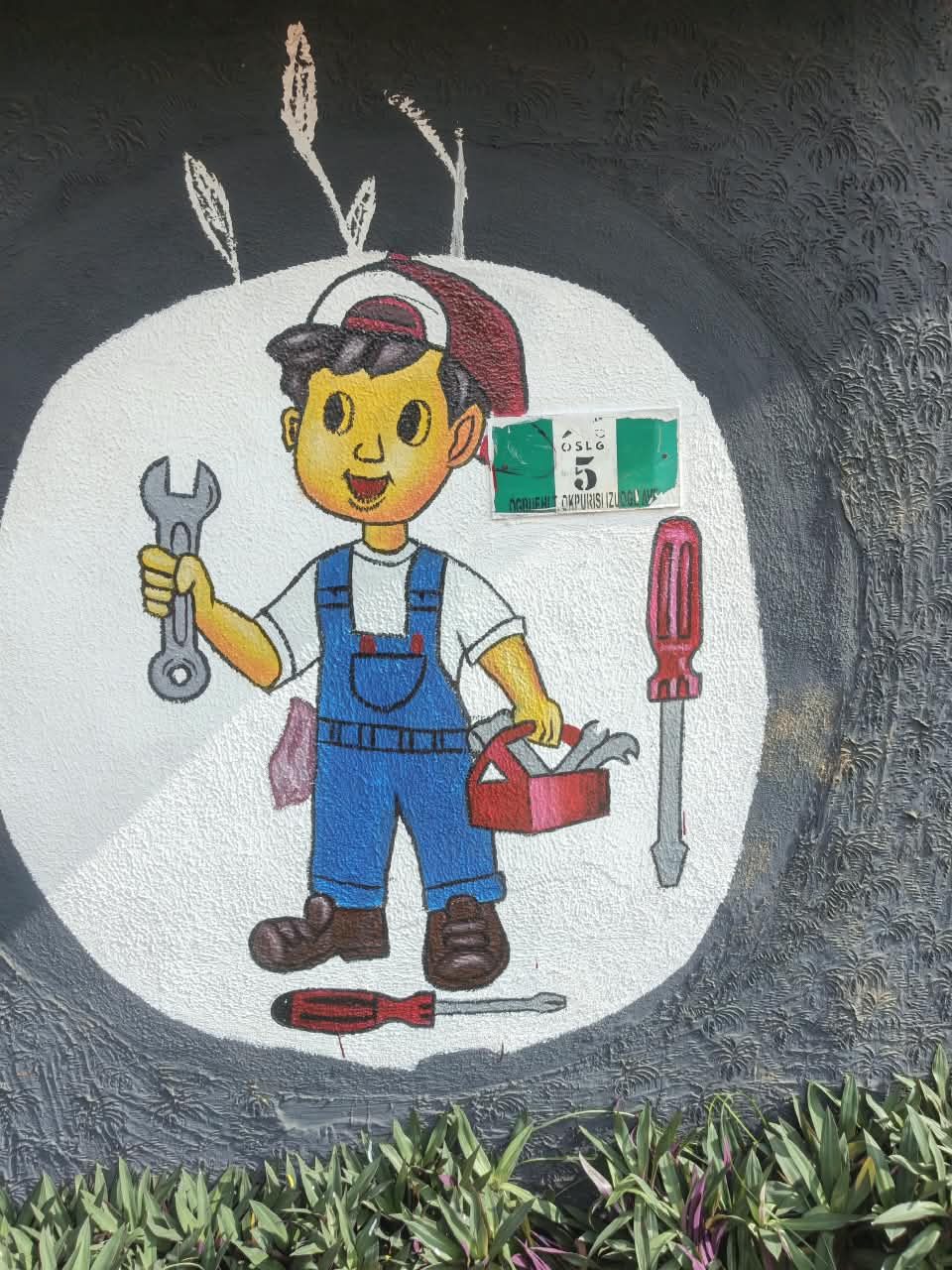 School wall mural of a smiling mechanic holding a spanner and toolbox